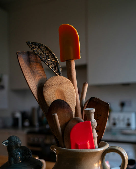 A cup filled with wooden utensils on top of a table